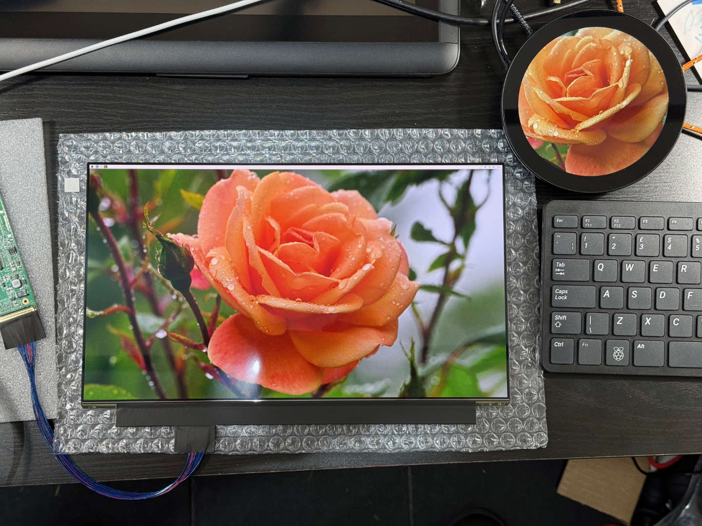 Two screens, one round and one rectangular showing the same image of a rose, both are connected to a Raspberry Pi
